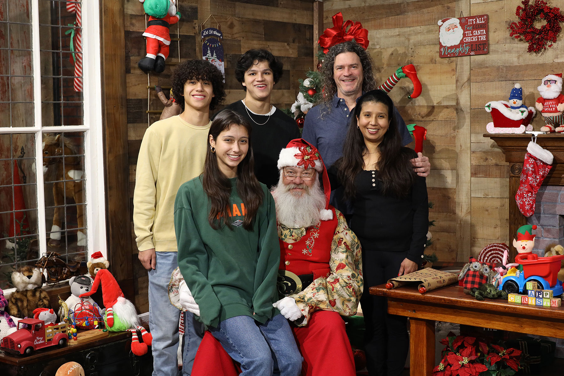 family with grown children posing for photos with Santa