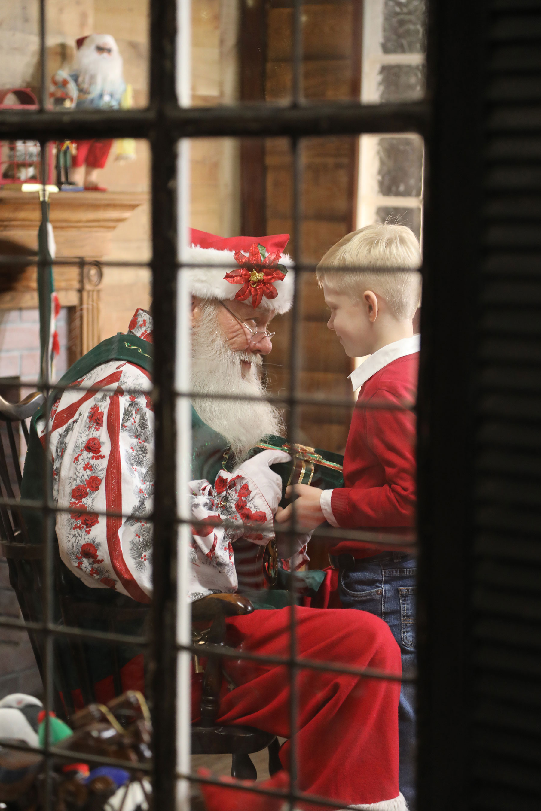 photo through a window of Santa giving a little boy a present