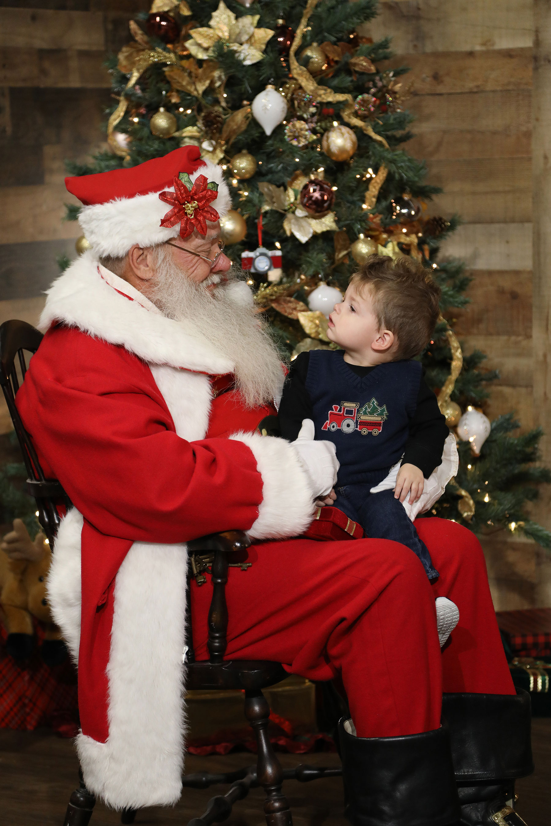 toddler sitting on santa's lap looking curiously at him