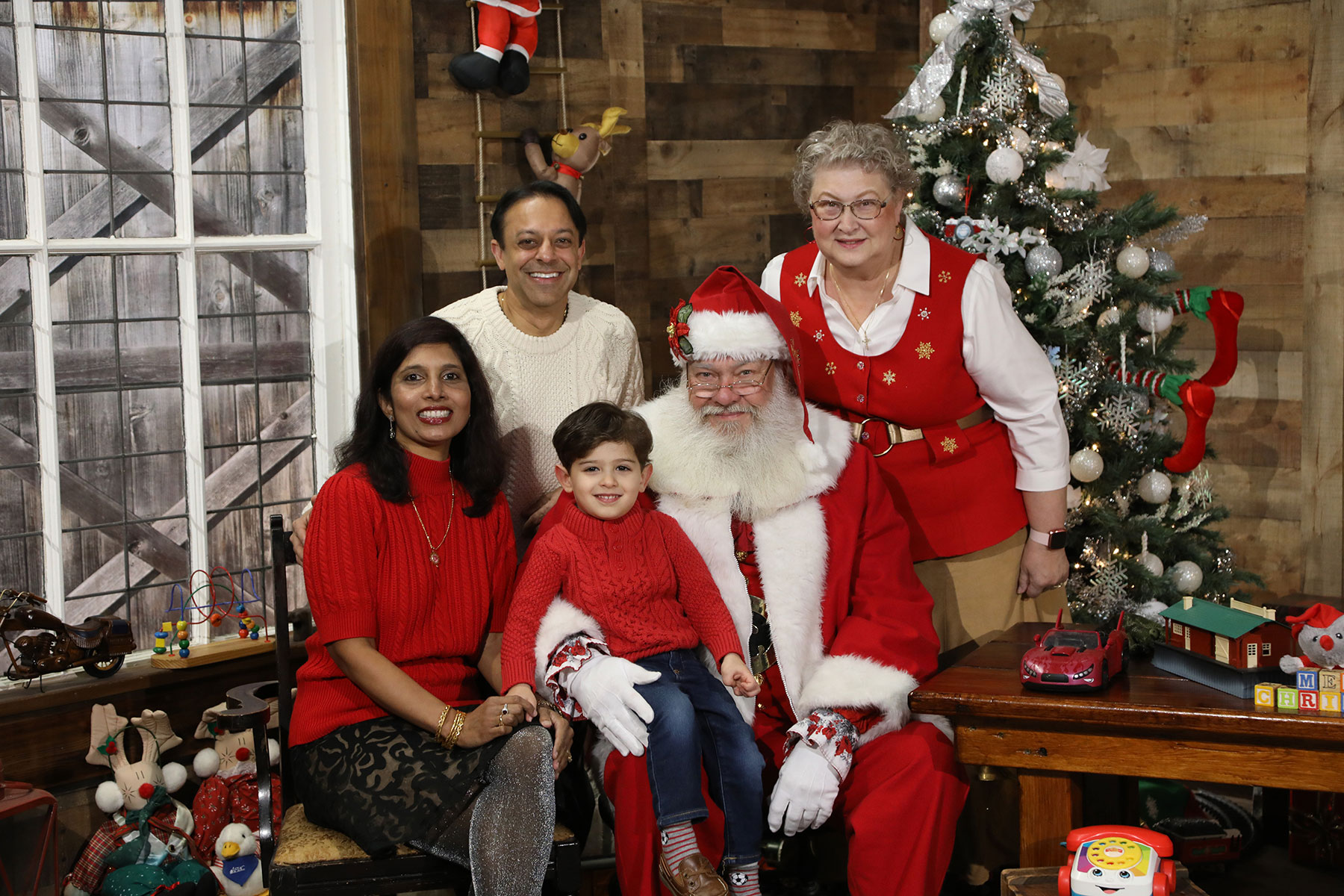 family of three posing for a christmas photo with Santa and Mrs. Claus