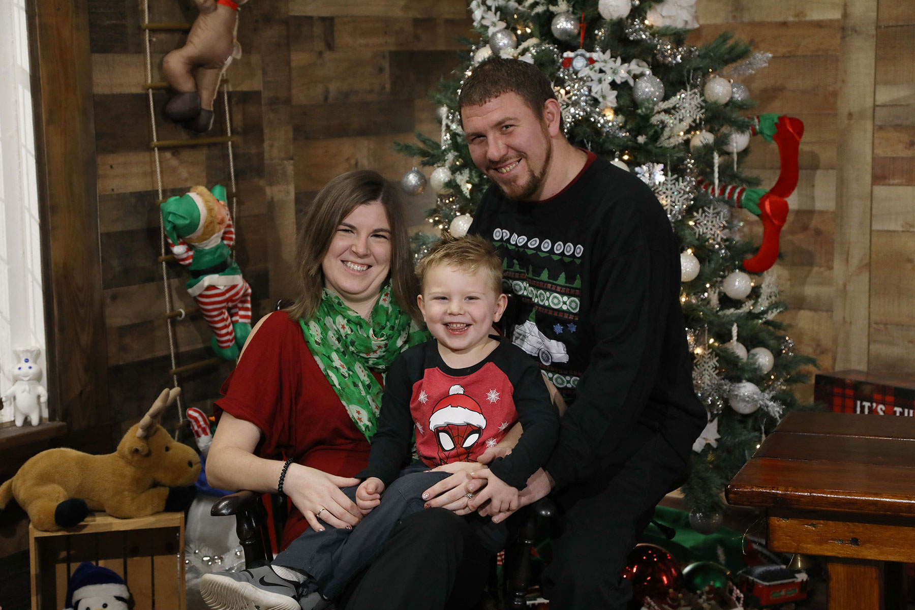 mom, dad, and toddler son posing for a photo near a christmas tree