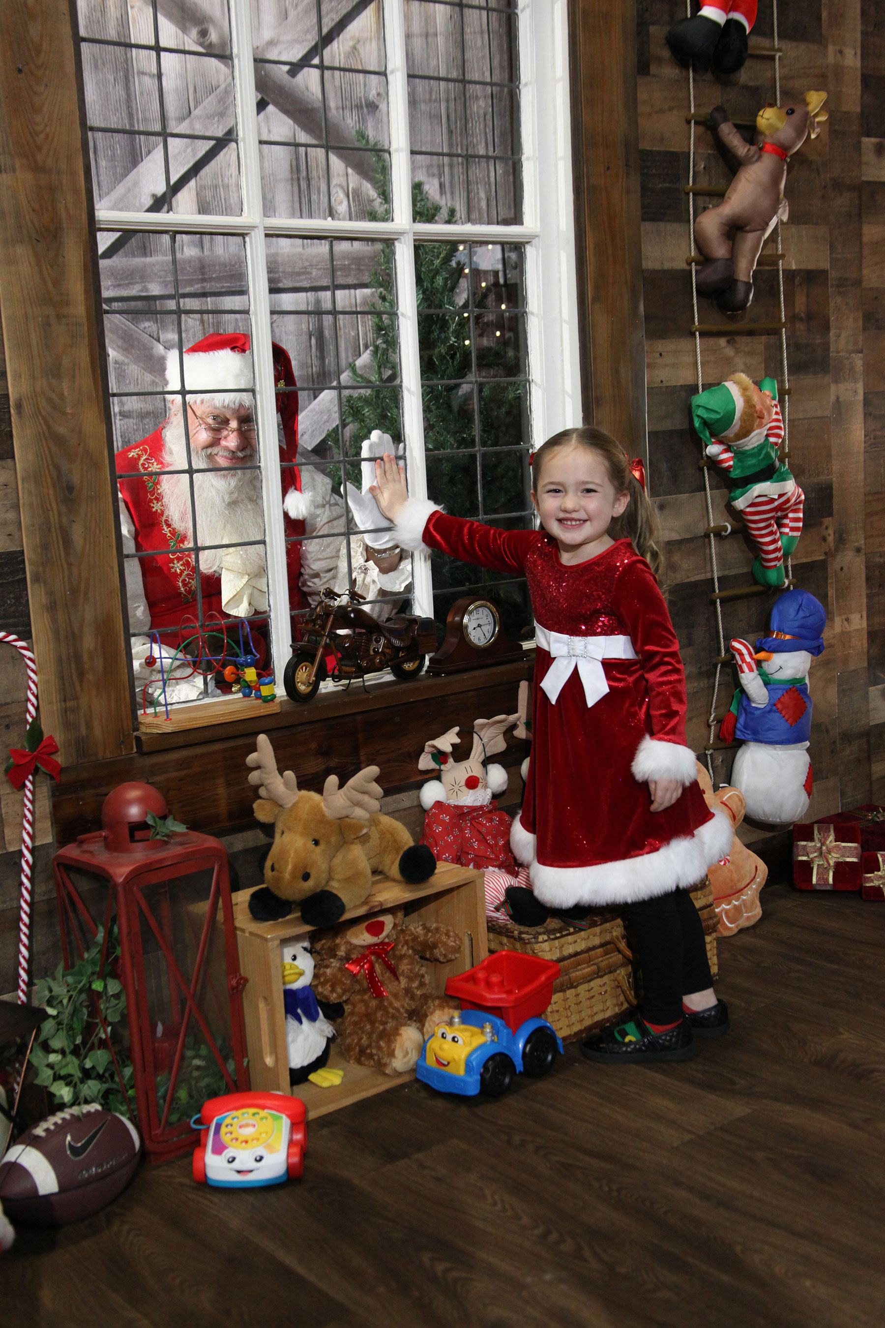 a little girl holding her hand up to a window with santa doing the same thing on the other side