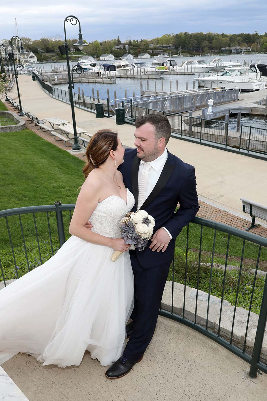 the bride and groom are gazing into each other's eyes while standing on the monument at Charlevoix Harbor