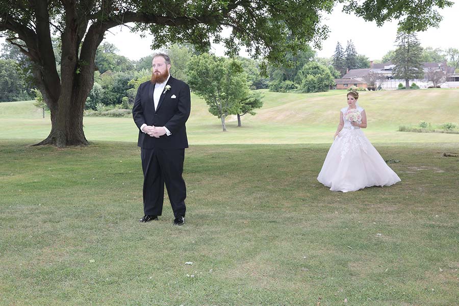 the bride is coming up from behind the groom for their first look before their wedding at Tamaron Country Club