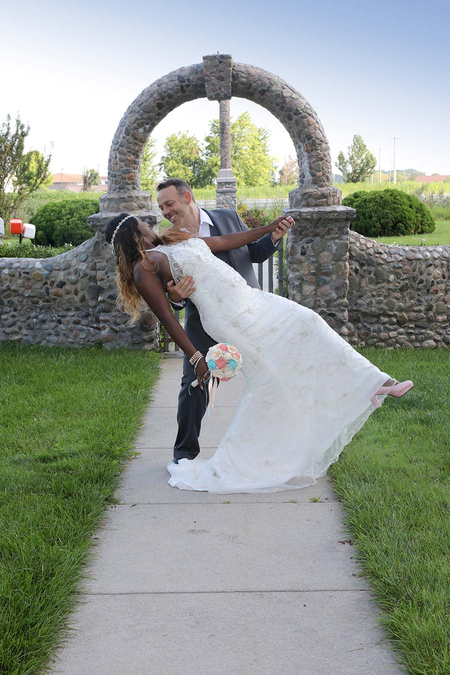 picture of the bride and groom posing as the groom dips the bride in front of the archway at the Wood County Historical Center and Museum