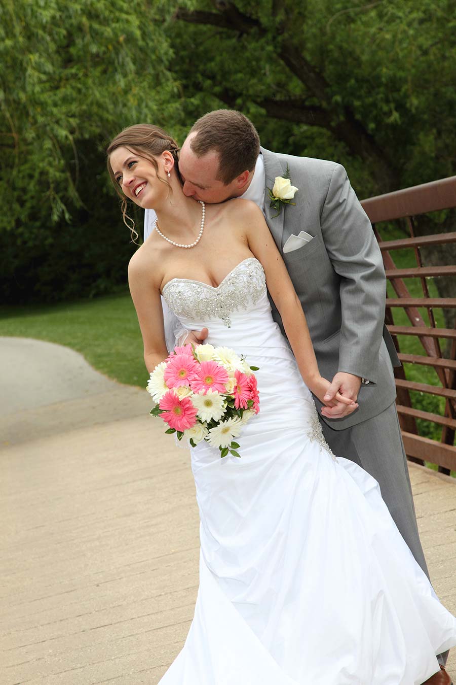 the groom gently kisses his bride's neck while she smiles
