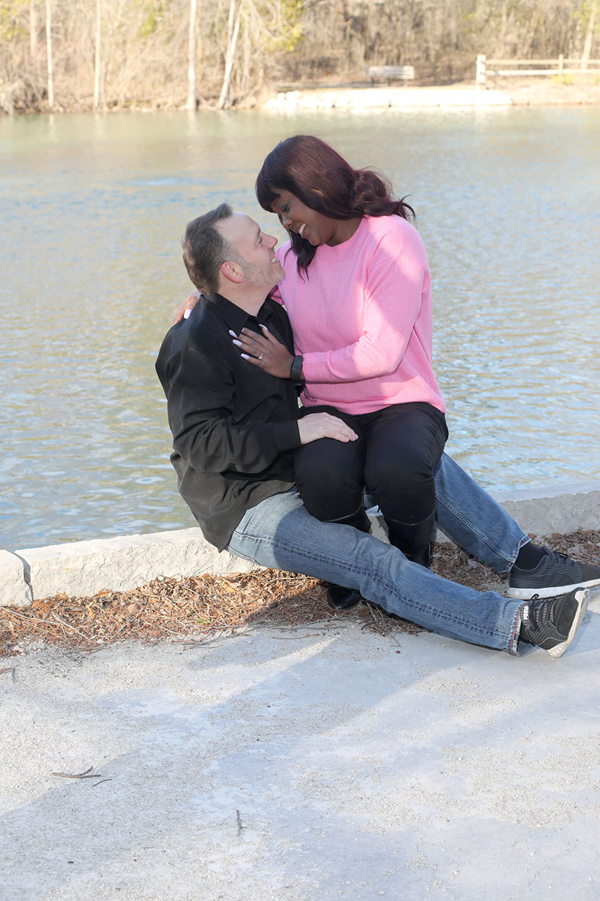 engaged couple sitting on the bank of the river looking into each others eyes