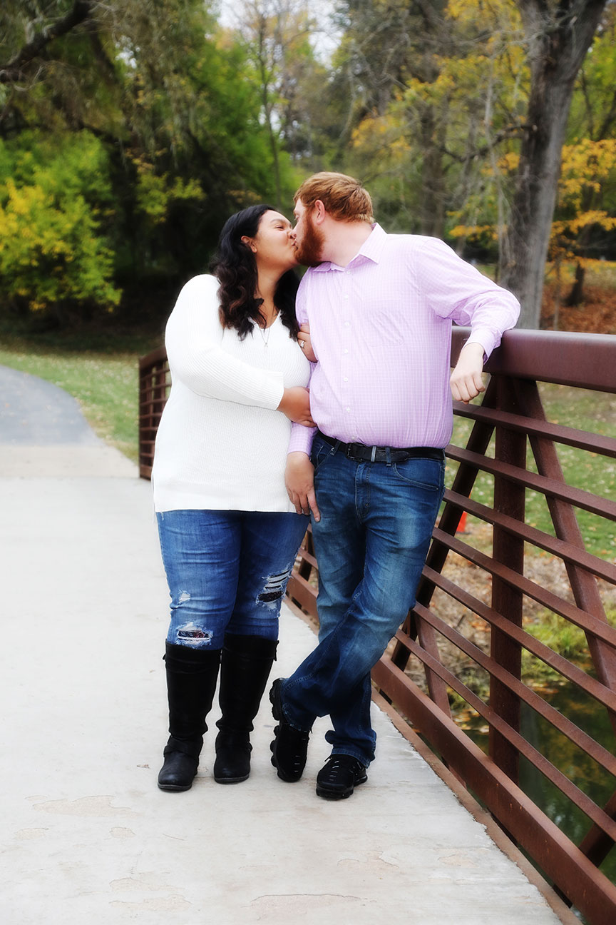 fall engagement photos are popular as seen in this image of a couple stopping for a kiss on a bridge at Side Cut Metropark in Maumee Ohio