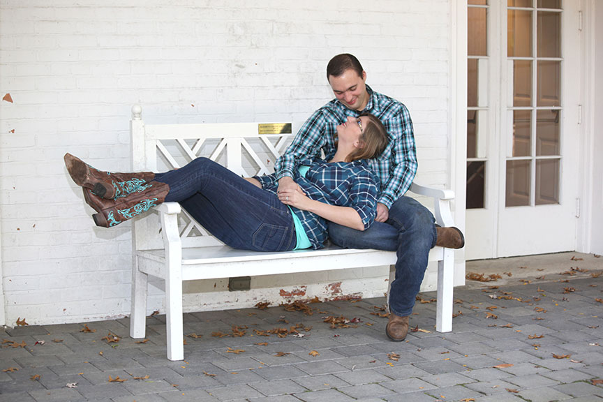 engaged couple sitting on the white park bench behind the manor house at Wildwood MetroPark