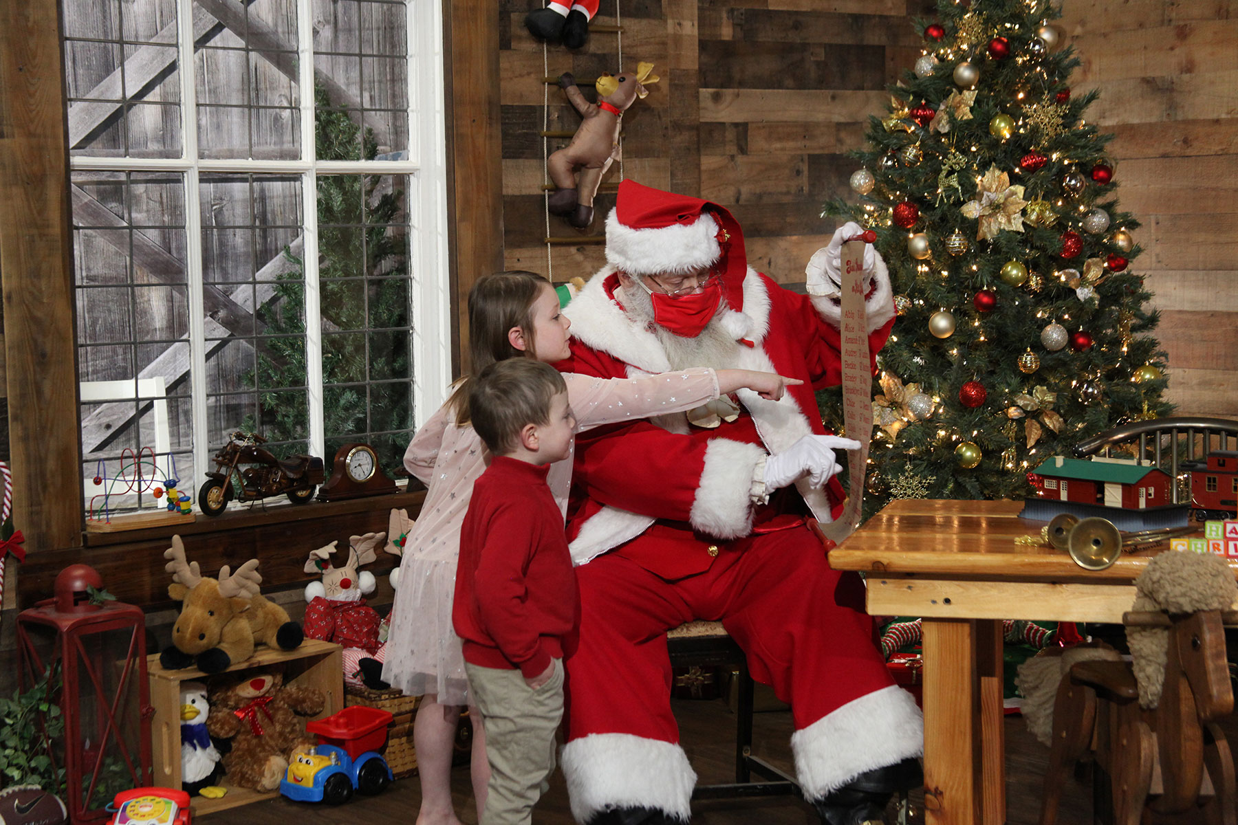 brother and sister pointing to their names on Santa's nice list 